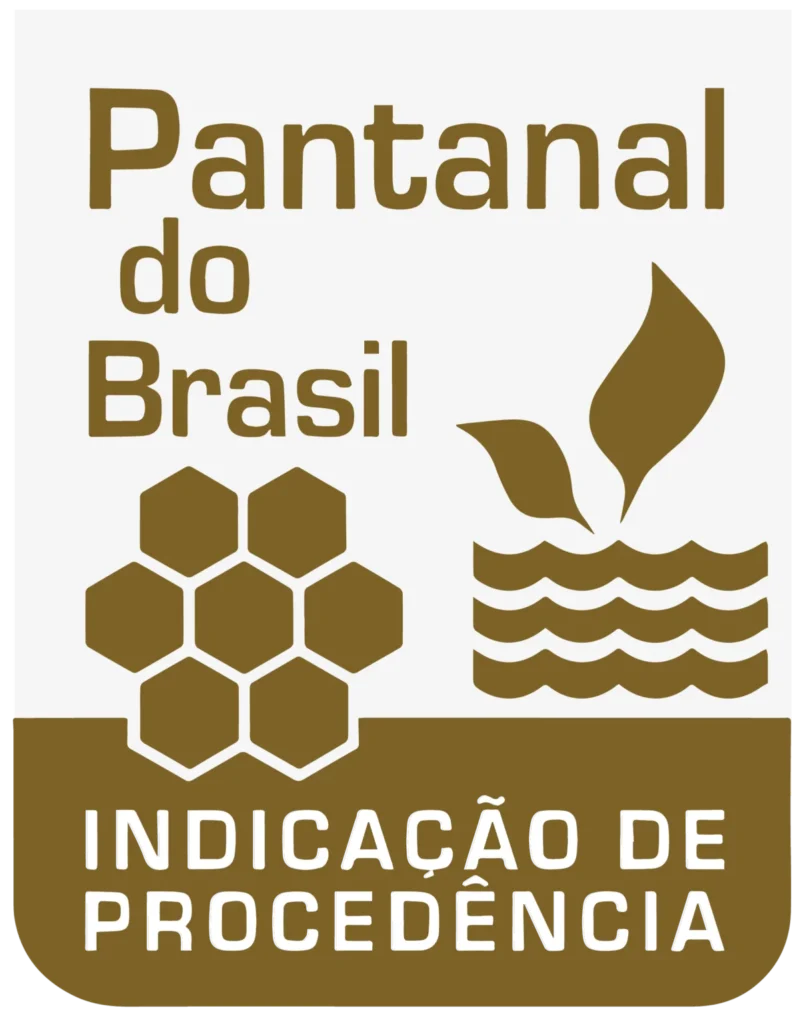 Imagem colorida em orientação vertical onde é apresentado o selo de Indicação de Procedência Pantanal do Brasil. Sua cor é majoritariamente marrom claro e consiste das palavras "Pantanal do Brasil" em cor marrom claro e fundo branco acinzentado, e "Indicação de Procedência" em cor branca e com um fundo marrom claro. Também há uma ilustração de favo de mel em cor marrom claro e duas folhas dentro da água e também de cor marrom claro.